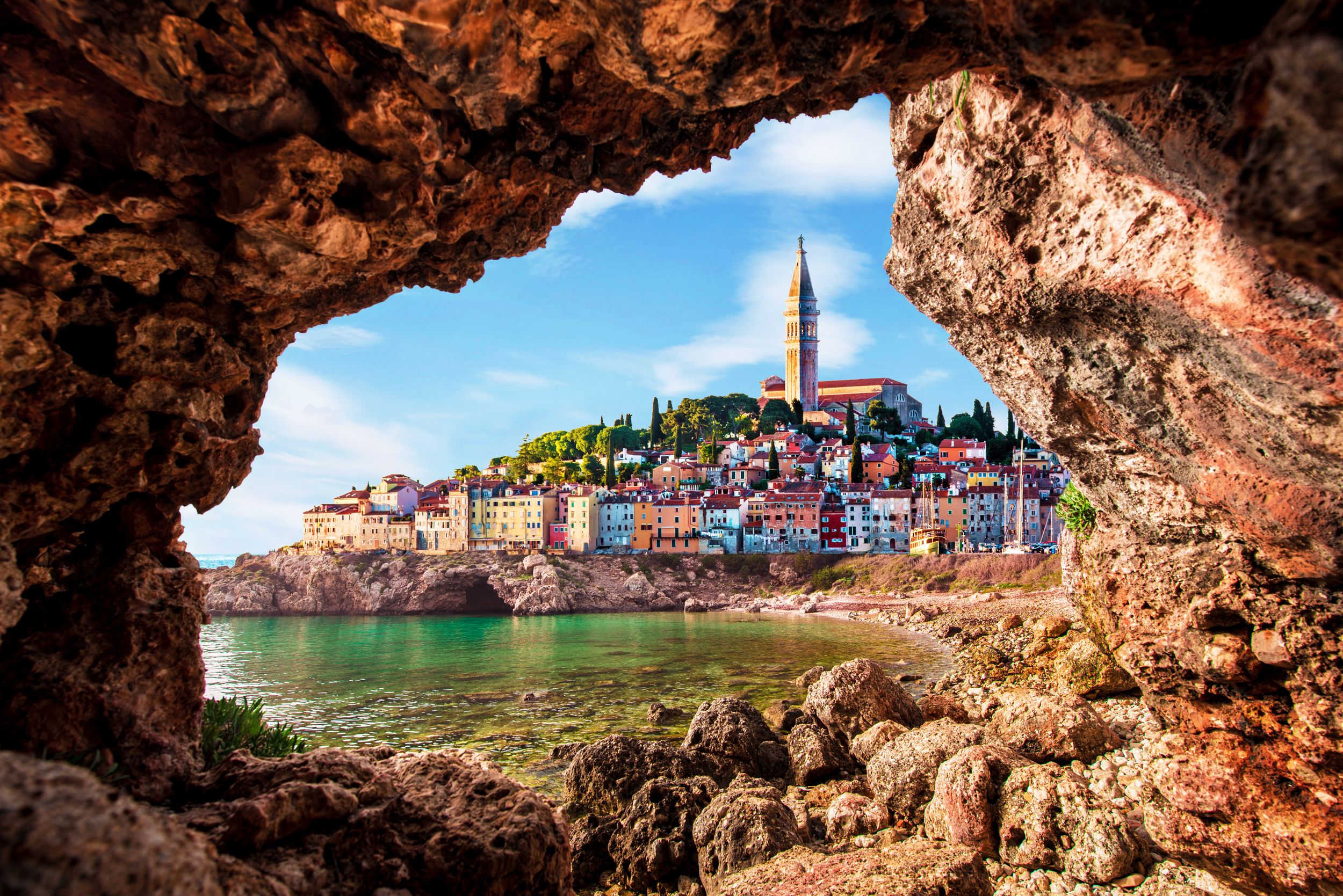 Unusual view with old clock towe in Piran through a rock hole. the tou