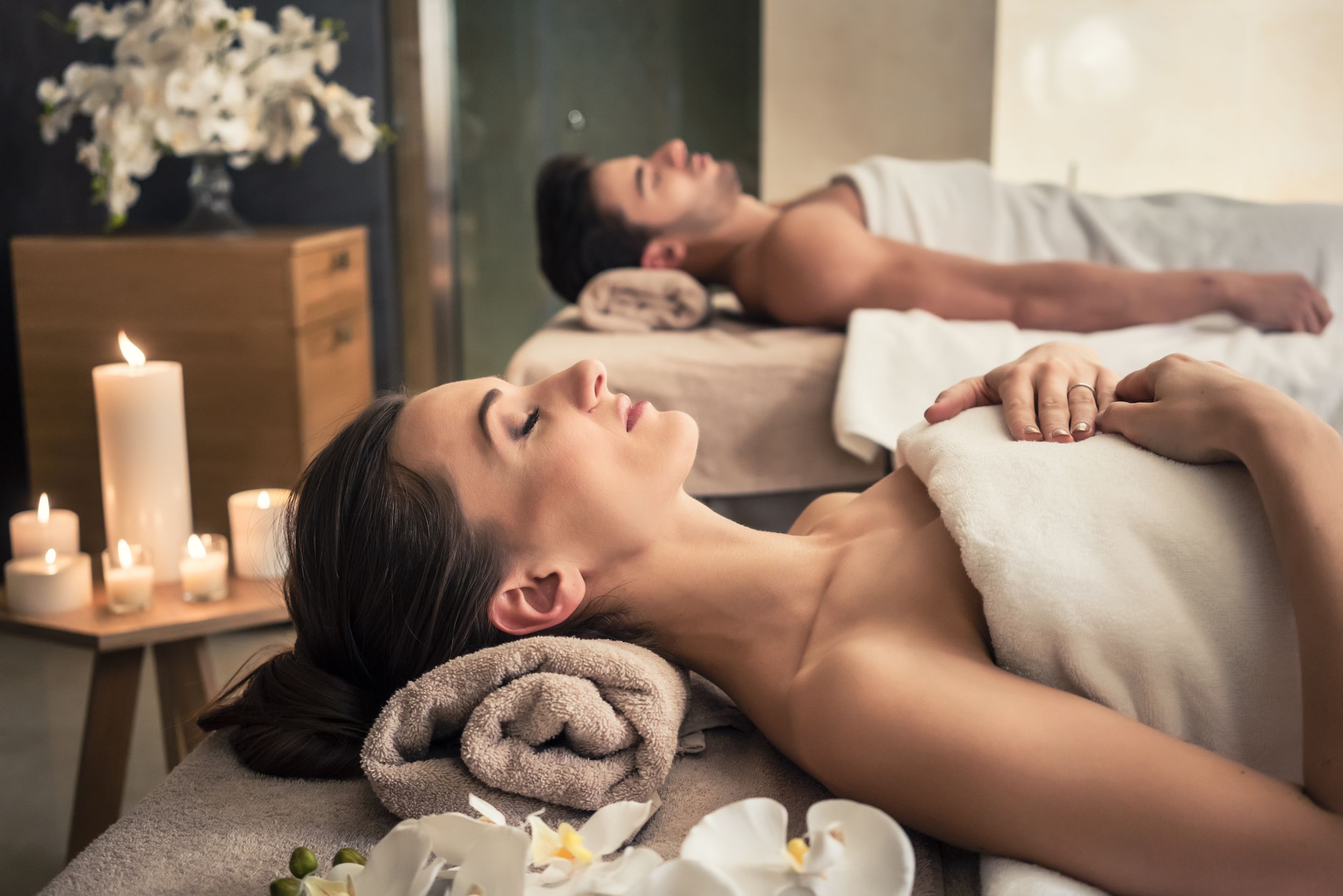 Young man and woman lying down on massage beds at Asian luxury spa and