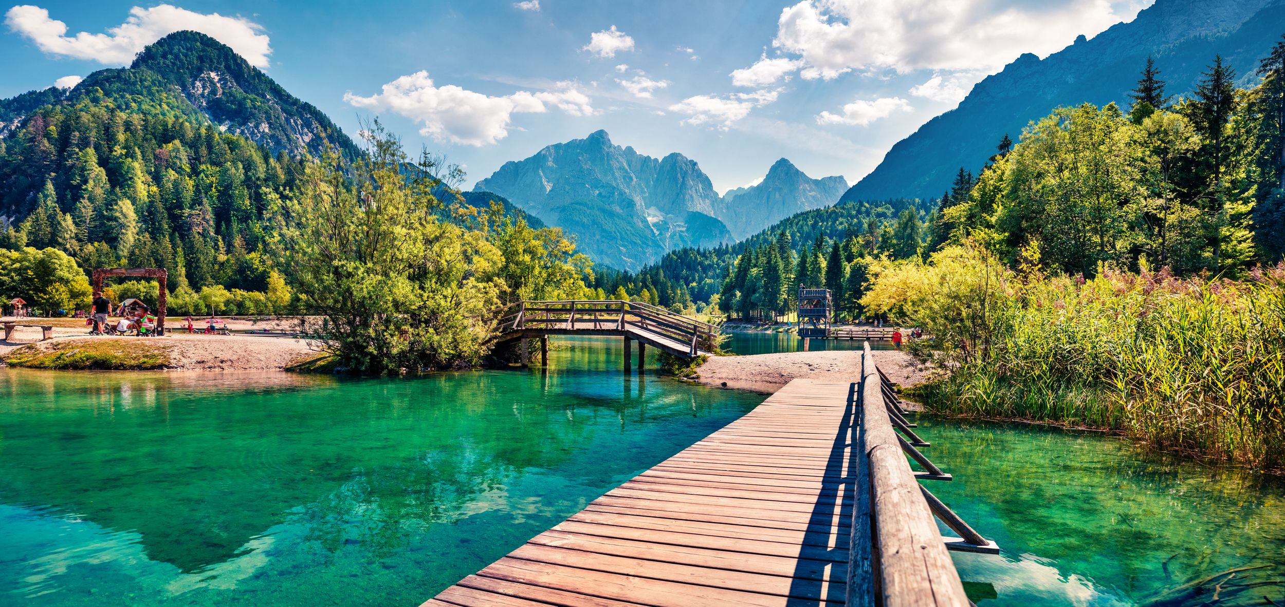 Wooden bridge over the Jasna lake. Panoramic summer view of Julian Alp
