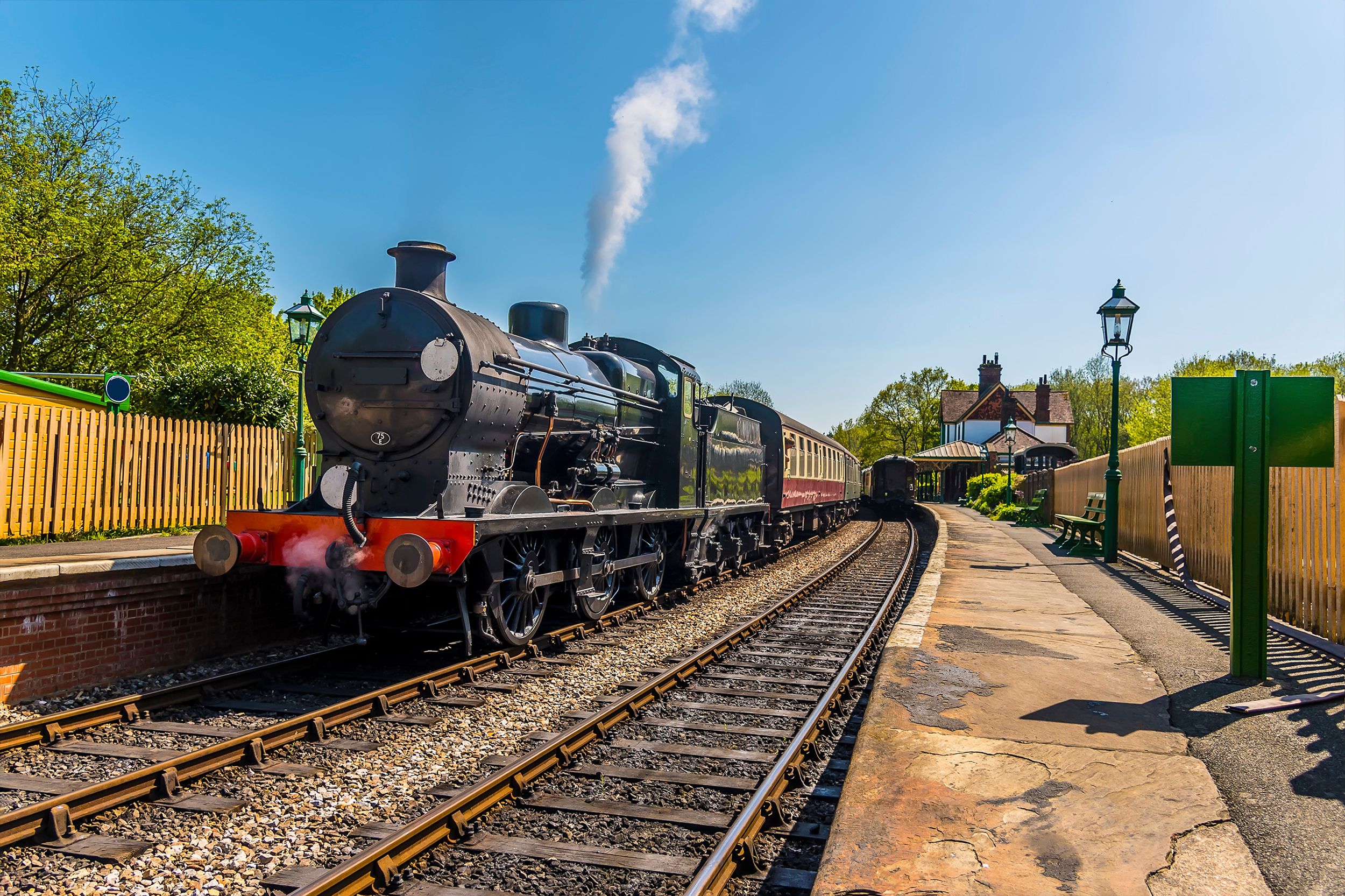 Steam trains at a station on a railway line in Sussex, UK on a sunny s