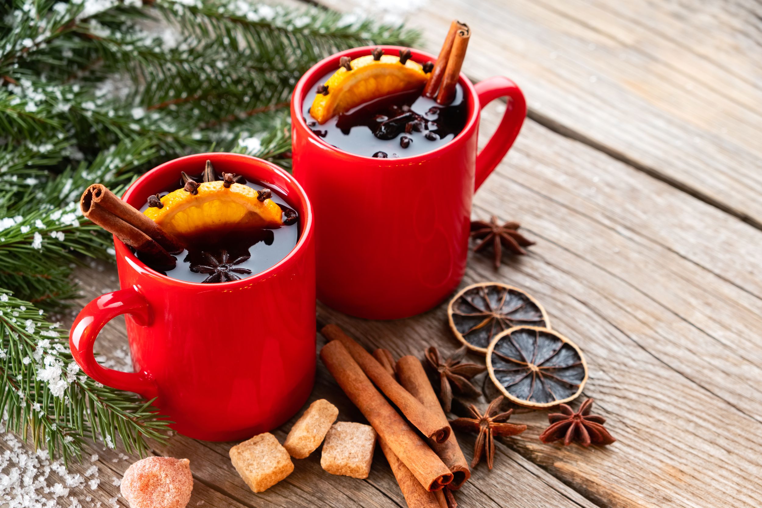 Red mugs of hot mulled wine with spices and citrus fruits and Christma