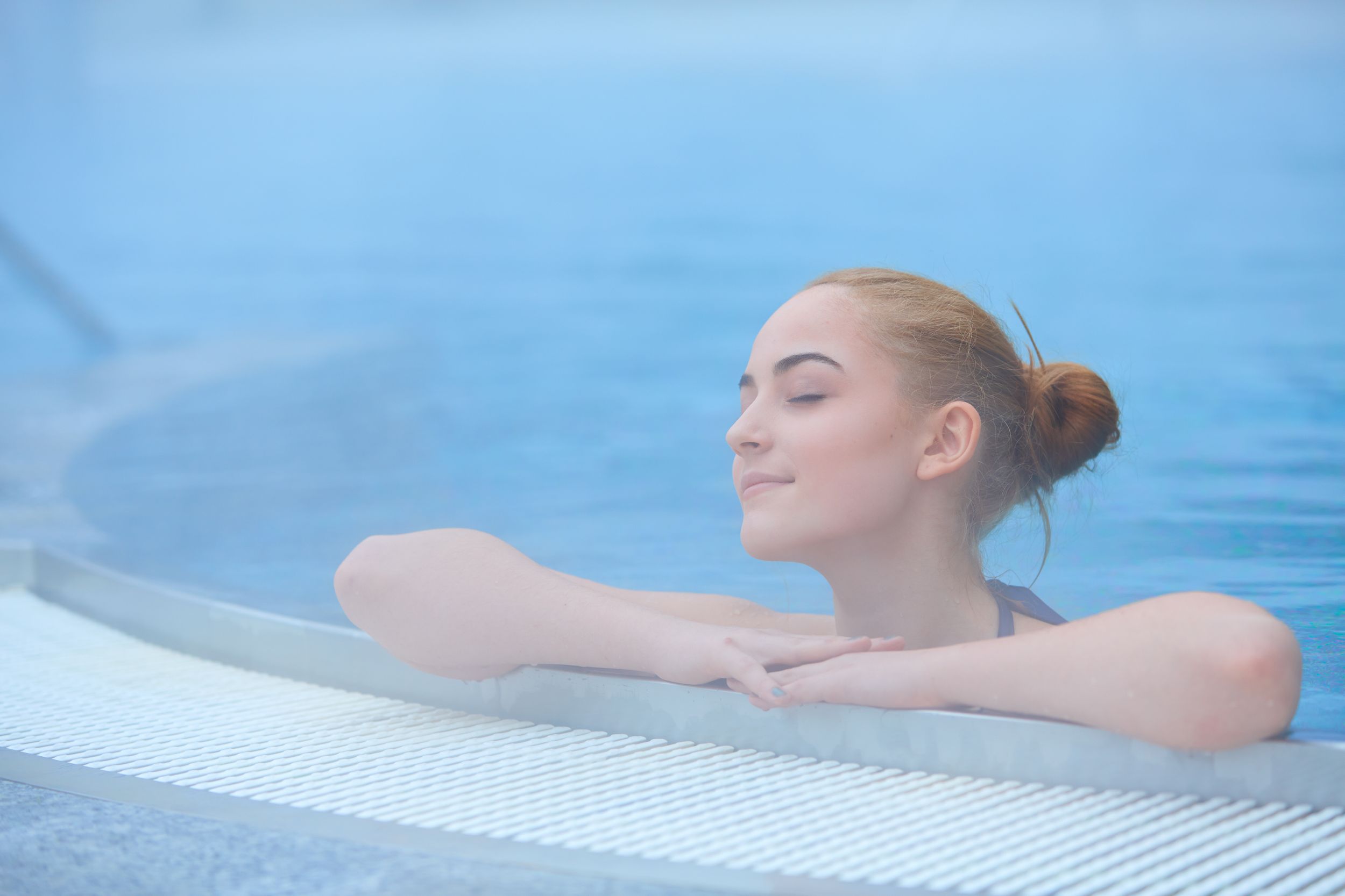 Young woman in outside thermal pool at wintertime, relaxed