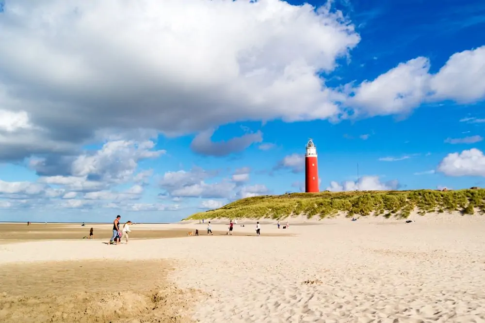 Beach with people and lighthouse of De Cocksdorp on island Texel, Nort