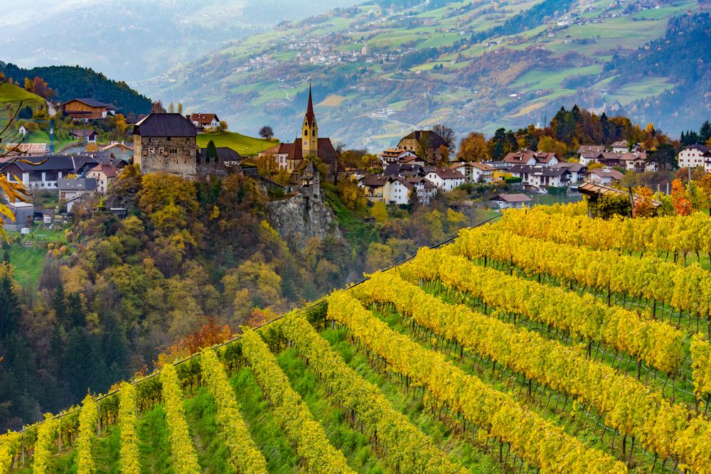 Herbstliche Weinberge undein malerisches Dorf im Eisacktal mit Kirche und Schloss 